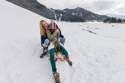 Zwei junge Frauen auf einem Schlitten, Spitzingsee, Oberbayern, Bayern, Deutschland