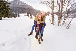 Young woman giving friend a piggyback ride, Spitzingsee, Upper Bavaria, Germany