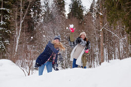 Zwei junge Frauen bei einer Schneeballschlacht, Spitzingsee, Oberbayern, Bayern, Deutschland