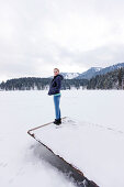 Young woman on a jetty at lake Spitzingsee, Upper Bavaria, Germany