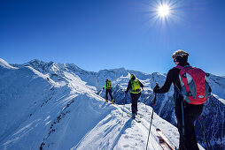 Three persons back-country skiing ascending on snow-ridge, Zillertal Alps in background, Gammerspitze, valley of Schmirn, Zillertal Alps, Tyrol, Austria