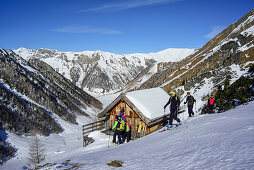 Mehrere Personen auf Skitour stehen an Almhütte, Frauenwand, Schmirntal, Zillertaler Alpen, Tirol, Österreich