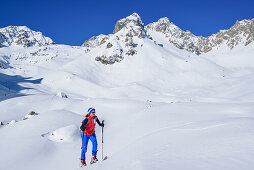 Woman back-country skiing ascending to Col Sautron, Monte Sautron in the background, Col Sautron, Valle Maira, Cottian Alps, Piedmont, Italy