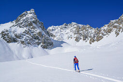 Woman back-country skiing ascending to Col Sautron, Monte Sautron in the background, Col Sautron, Valle Maira, Cottian Alps, Piedmont, Italy