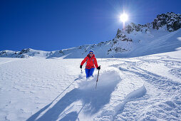 Woman back-country skiing downhill through powder snow from Passo Croce, Passo Croce, Valle Maira, Cottian Alps, Piedmont, Italy