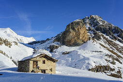Snow-covered alpine hut in front of Rocca Senghi, Monte Salza, Valle Varaita, Cottian Alps, Piedmont, Italy