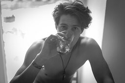 Young man at home, having a drink of water, indoors