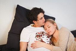 Young couple relaxing on the sofa, Hugging, Pensive