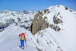 Woman back-country skiing ascending on ridge towards Piz Lischana, Piz Lischana, Sesvenna Alps, Engadin, Grisons, Switzerland