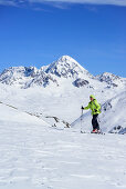 Woman back-country skiing ascending towards Pizzo Tresero, Koenigsspitze in background, Pizzo Tresero, Val dei Forni, Ortler range, Lombardy, Italy