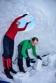 Two persons building igloo, Chiemgau range, Chiemgau, Upper Bavaria, Bavaria, Germany
