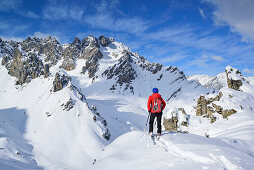 Woman back-country skiing looking towards valley Vallonasso di Sautron, Monte Soubeyran, Valle Maira, Cottian Alps, Piedmont, Italy