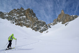 Woman back-country skiing ascending towards Colle d'Enchiausa, Valle Enchiausa, Valle Maira, Cottian Alps, Piedmont, Italy