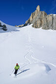 Woman back-country skiing downhill from Colle d'Enchiausa, Valle Enchiausa, Valle Maira, Cottian Alps, Piedmont, Italy