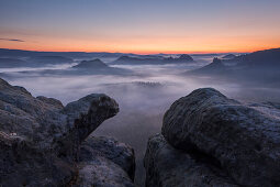 View from Gleitmannshorn over the small Zschand with fog at dawn with rocks in foreground, Little Winterberg, National Park Saxon Switzerland, Saxony, Germany