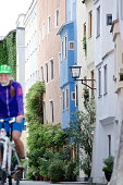 Female cyclist passing old town, Burghausen, Chiemgau, Bavaria, Germany