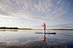 Frau beim Stand Up Paddling auf dem Chiemsee, Chiemgau, Bayern, Deutschland