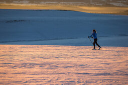 Young woman cross-country skiing at sunset, Allgauu, Bavaria, Germany