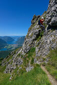 Woman climbing the Via ferrata del Centenario in front of Lake Lugano, Italy and Switzerland