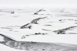 Schneestrukturen und verschneite Hügel in Winterlandschaft bei Höfn, Ostisland, Island, Europa