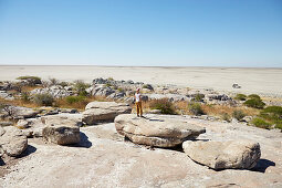 Woman standing on a rock while looking over salt desert, Kubu Island, Makgadikgadi Pans National Park, Botswana