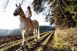 Mädchen reitet in weißem Kleidchen auf Pferd, Freising, Bayern, Deutschland