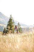Junge Frau fährt mit ihrem Fahrad bei einer Wiese an einem sonnigen Tag, Tannheimer Tal, Tirol, österreich