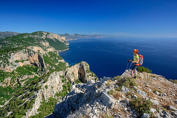 Frau wandert am Selvaggio Blu über Felsgrat mit Blick auf Mittelmeer, Selvaggio Blu, Nationalpark Golfo di Orosei e del Gennargentu, Sardinien, Italien