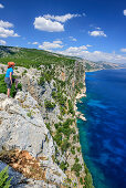 Frau beim Wandern blickt über Steilküste auf Golfo di Orosei, Selvaggio Blu, Nationalpark Golfo di Orosei e del Gennargentu, Sardinien, Italien