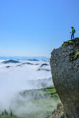 Woman hiking standing on  molasse conglomerate, fog in the valley, Hochgrat, Nagelfluh range, Allgaeu Alps, Allgaeu, Svabia, Bavaria, Germany