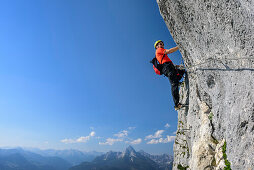 Man ascending fixed rope route, Watzmann in background, Hochthronklettersteig, fixed rope route Hochthron, Untersberg, Berchtesgadener Hochthron, Berchtesgaden Alps, Upper Bavaria, Bavaria, Germany