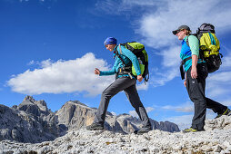 Zwei Frauen wandern über Felsgelände, Cimon della Pala und Cima della Vezzana im Hintergrund, Pala, Dolomiten, UNESCO Weltnaturerbe Dolomiten, Trentino, Italien