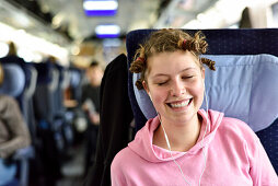Girl listening to music with earphones in a train, Germany, Europe