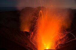 High lava eruption of the main crater of the active volcano Yasur with lava bombs and toxic gases. Small eruption of the crater next to Yasur. Overcast, dark sky during the blue hour. - Vanuatu, Tanna Island, South Pacific