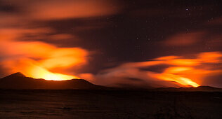 Blick auf die Vulkane Marum und Benbow in weiter Entfernung bei Nacht. Lava leuchtet die Gase und den nächtlichen Sternenhimmel Blutrot aus, Vanuatu, Insel Ambrym, Süd Pazifik