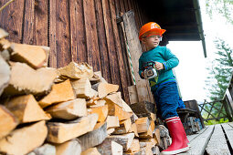 4 year old boy dressed as a woodcutter with a toy saw in his hand, alpine hut, Maria Alm, Berchtesgadener Alpen, Alps, Austria, Europe