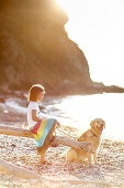 Six year old girl with labrador on pebble beach at Portoferraio, Elba, Tuscany, Italy