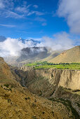 Surreale Landschaft typisch fuer das Mustang in der Hochwueste um das Kali Gandaki Tal, dem tiefsten Tal der Welt. Fruchtbare Felder gibt es in der Hochwueste nur durch ein ausgekluegeltes Bewaesserungssystem. Im Hintergrund die Gurung Ortschaft Ghyakar u