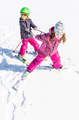 girl pulling a boy along the slope, Pfronten, Allgaeu, Bavaria, Germany