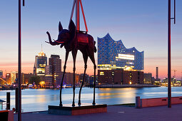 Sculpture of an elephant by Salvador Dali in front of the Stage Theatre, view over the Elbe river to the Elbphilharmonie, Hamburg, Germany