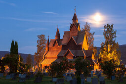 Heddal stave church with grave stones in a summer night with full moon, Notodden, Telemark, Norway, Scandinavia