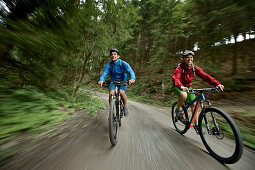 Cyclists riding down a path in a forest