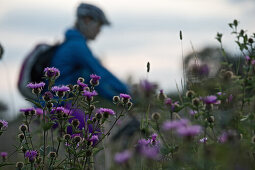 Young woman riding with her bike through a flower meadow