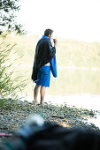 Young male camper brushing his teeth at a lake, Freilassing, Bavaria, Germany