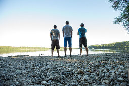 Three young men standing at a lake, Freilassing, Bavaria, Germany