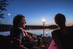 Zwei junge Männer liegen an einem See in der Nacht, Freilassing, Bayern, Deutschland