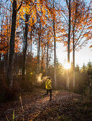 Young man running on a trail through a forest, Allgaeu, Bavaria, Germany