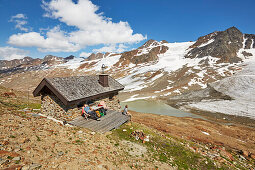 Paar sitzt vor Berghütte