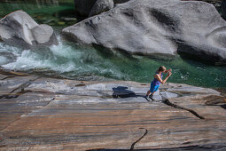 Wanderin steht auf einem Felsen an einem Fluss, Val Verzasca, Tessin, Schweiz