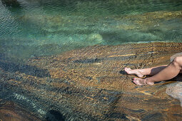 Young female hiker lying on a rock at a river, Valle Verzasca, Ticino, Switzerland